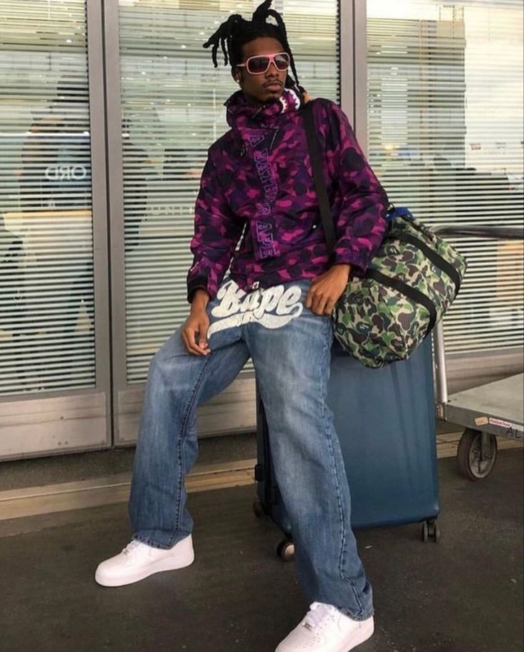 The ultimate Y2K cyber fashion look: purple camo hoodie, baggy jeans, a camo duffel bag and white sneakers